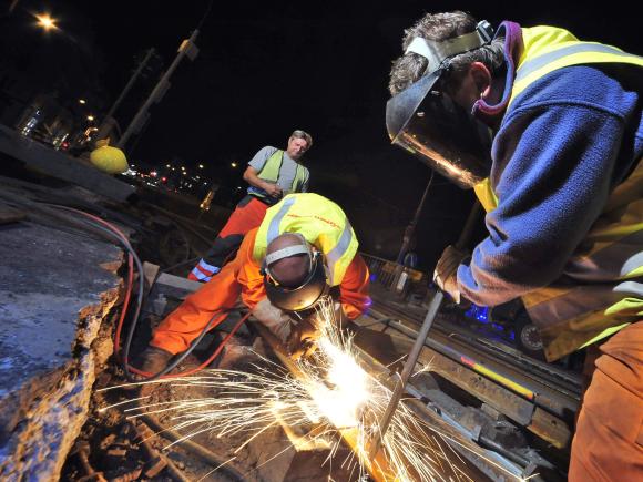 mehrere Personen bauen neue Gleise für eine Straßenbahn ein